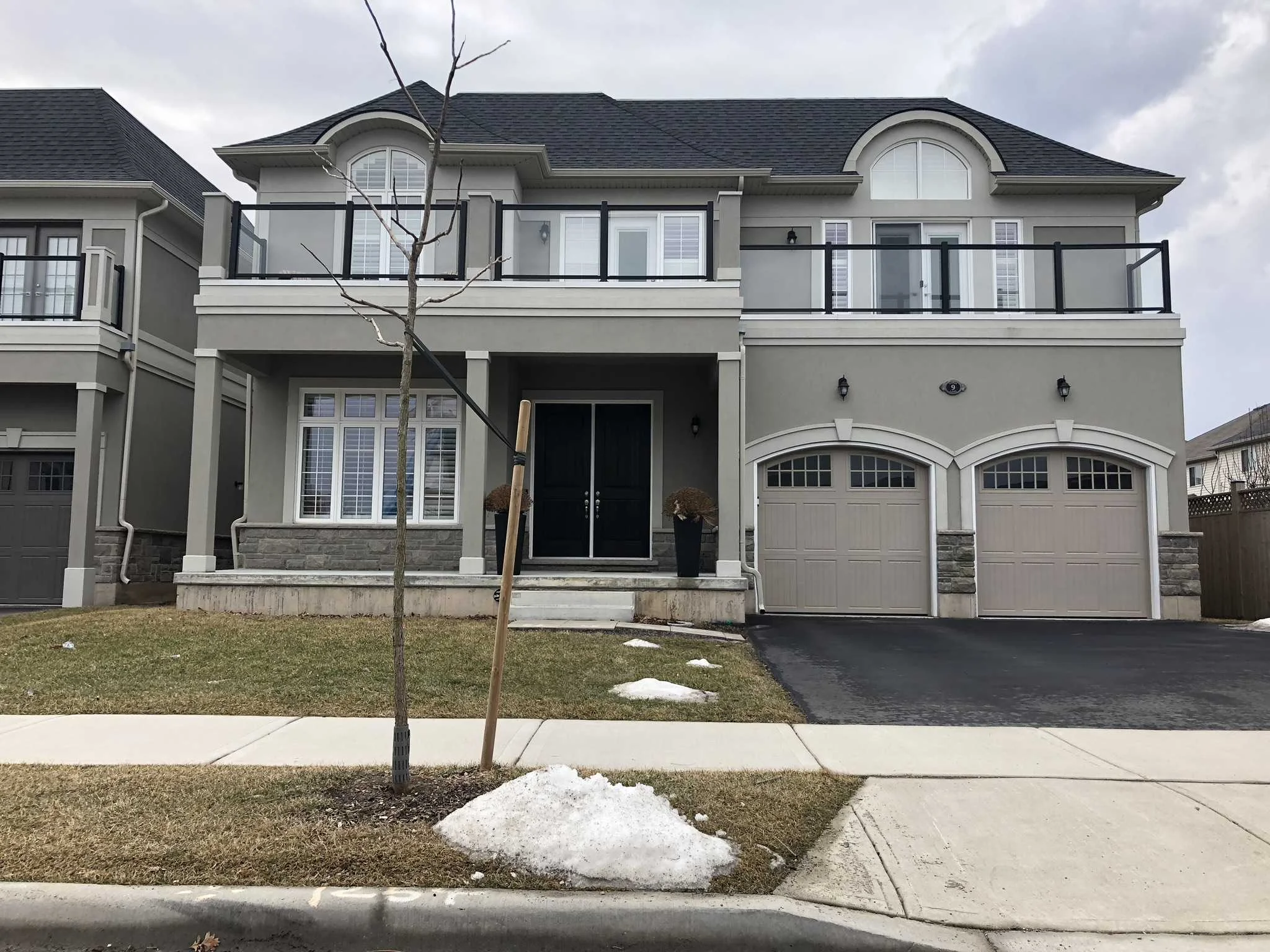 Two-storey stucco home with arched garage bays